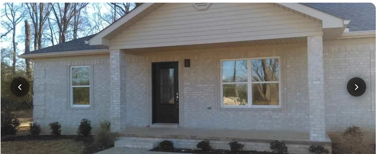 Front porch of a light brick home with black entry door