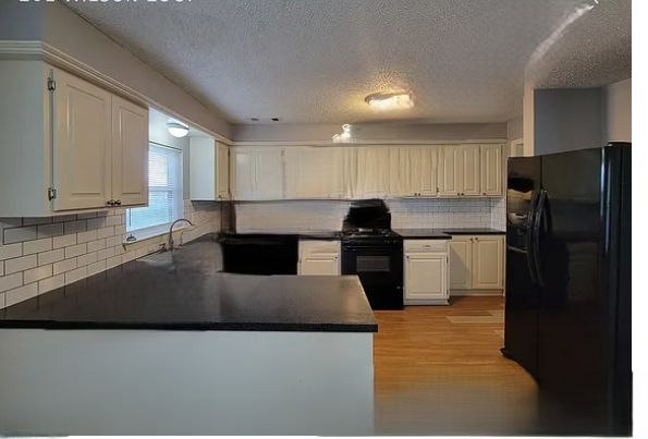 Kitchen with cream cabinets, black counters and subway tile